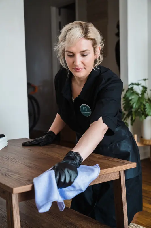 Schoonmaakster neemt een tafel af met een microvezeldoek